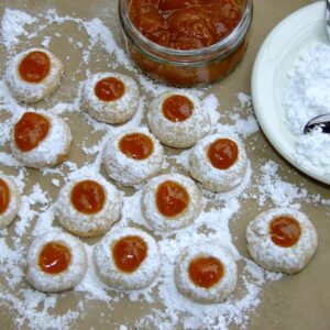 A group of blackberry cookies with dough underneath, jelly on the side and a plate beside it.
